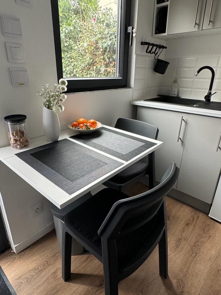 La table pliante du coin repas avec ses deux chaises noires